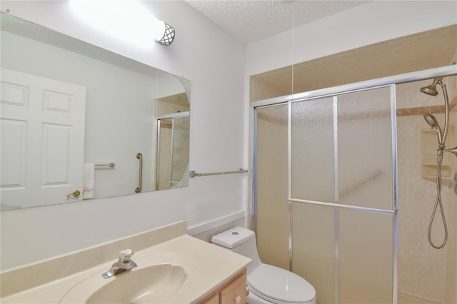 bathroom with vanity, a textured ceiling, a shower with door, and toilet