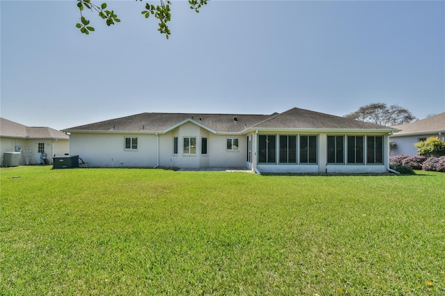 rear view of house with a yard, a sunroom, and central AC unit