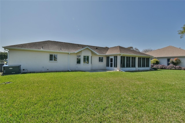 back of house featuring central air condition unit, a sunroom, and a lawn