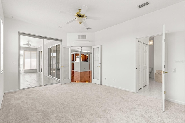 unfurnished bedroom featuring light colored carpet, ceiling fan, and connected bathroom