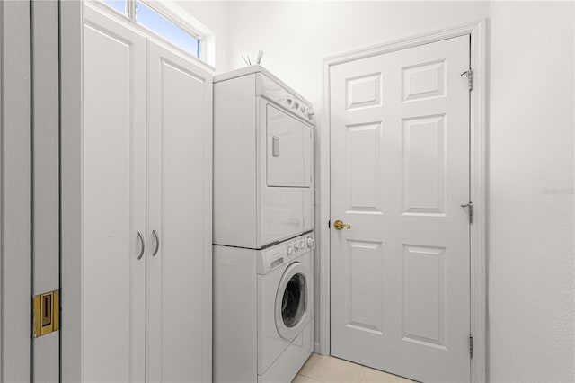 washroom featuring stacked washing maching and dryer and light tile flooring