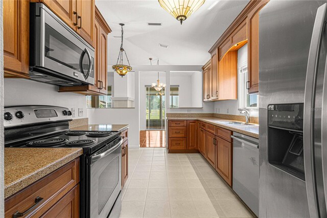 kitchen featuring an inviting chandelier, light tile floors, stainless steel appliances, sink, and hanging light fixtures