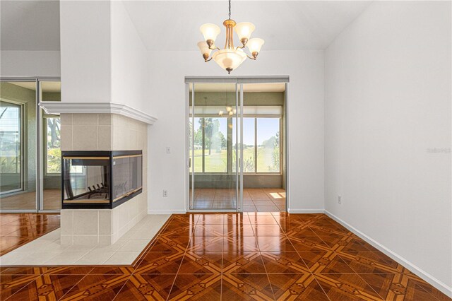 interior space featuring a tiled fireplace, an inviting chandelier, light parquet floors, and hanging light fixtures