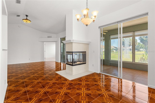 unfurnished living room featuring dark tile flooring, an inviting chandelier, a tile fireplace, and vaulted ceiling