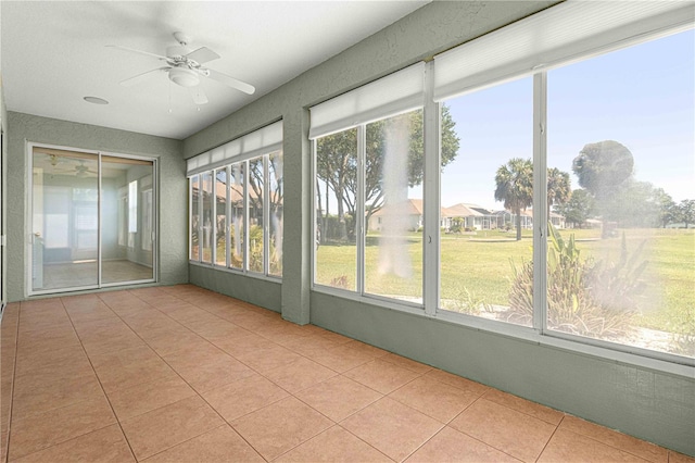 unfurnished sunroom featuring ceiling fan and a wealth of natural light