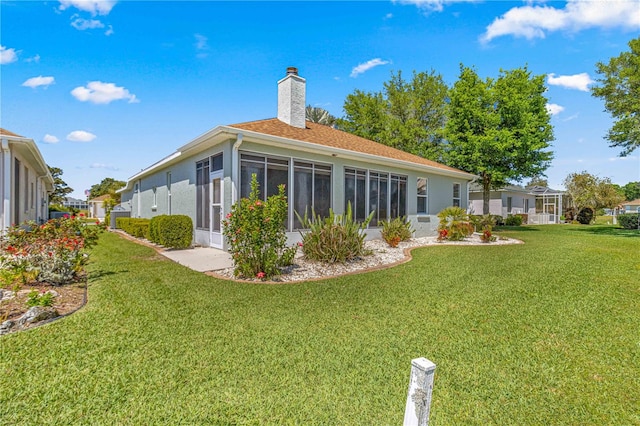 rear view of property with a sunroom and a lawn