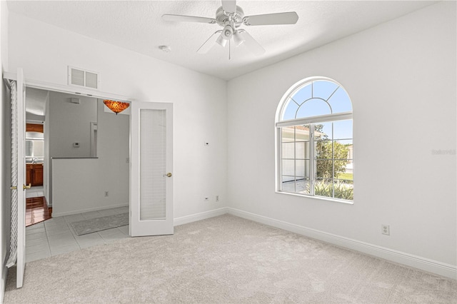 carpeted empty room featuring ceiling fan, a textured ceiling, and french doors