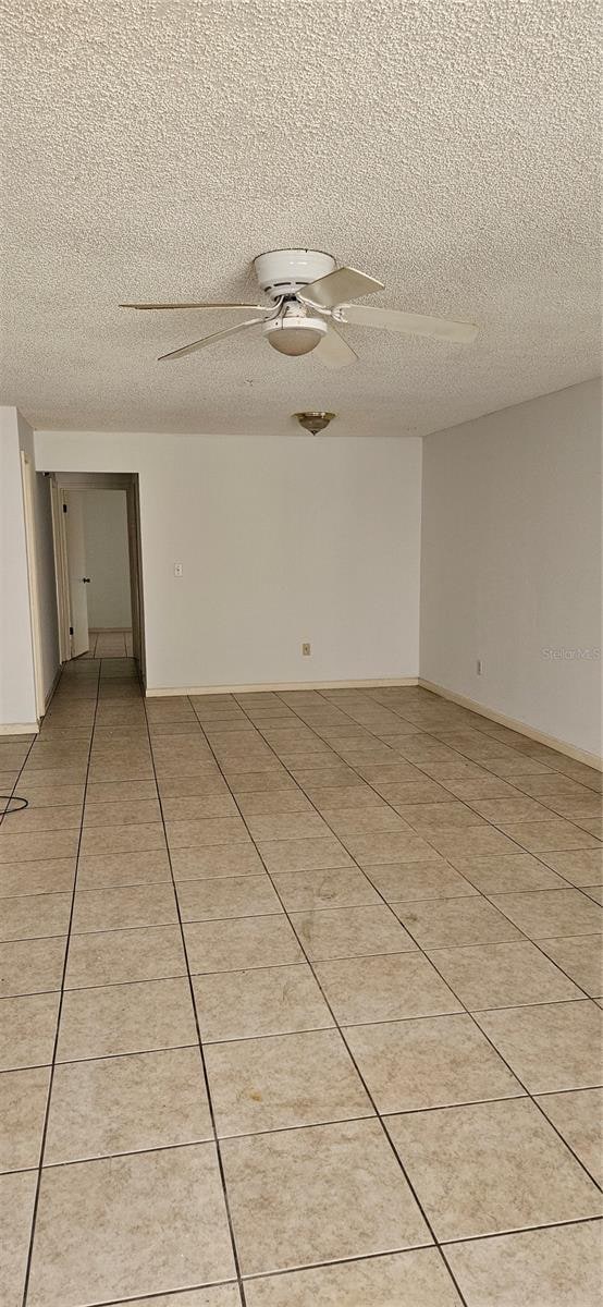 tiled spare room with ceiling fan and a textured ceiling