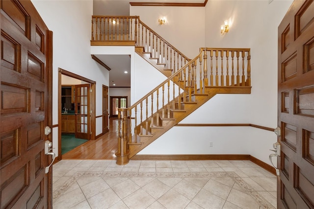 foyer featuring crown molding, a high ceiling, and tile patterned floors