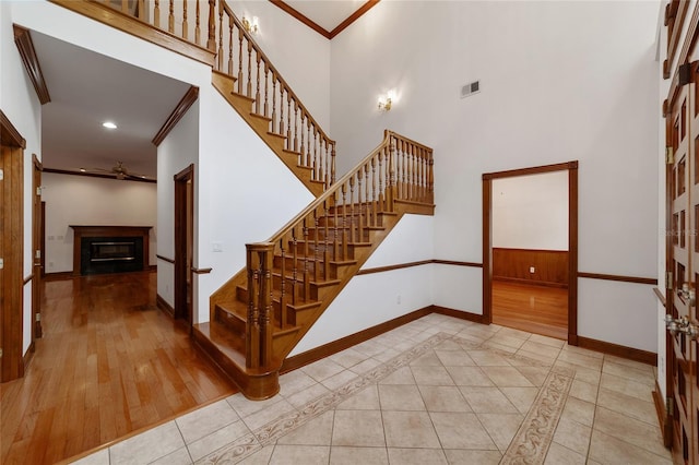 staircase featuring crown molding, a high ceiling, hardwood / wood-style floors, and ceiling fan