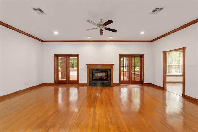 unfurnished living room with light wood-type flooring, a fireplace, ceiling fan, and french doors