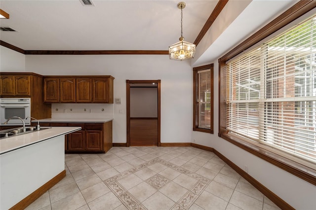 kitchen with an inviting chandelier, pendant lighting, ornamental molding, and sink