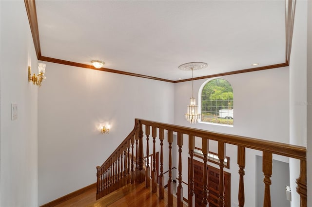 stairway with a notable chandelier, crown molding, and hardwood / wood-style flooring