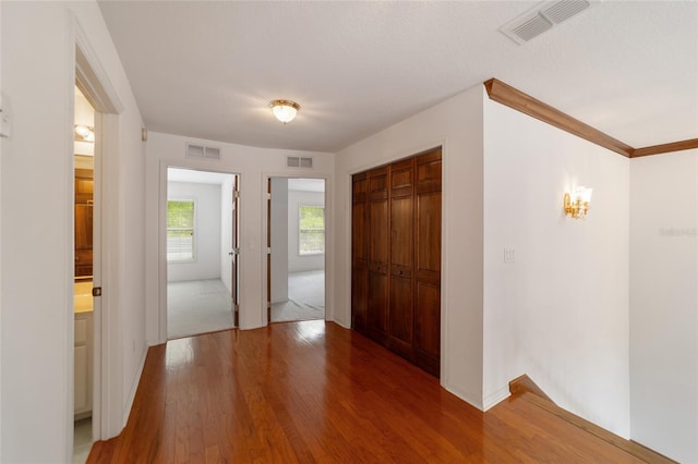 entryway with a textured ceiling, ornamental molding, and dark hardwood / wood-style flooring