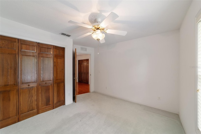 unfurnished bedroom with ceiling fan, a closet, and light carpet