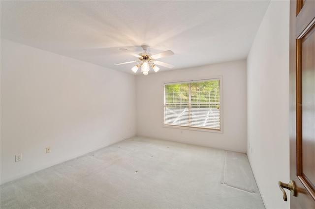 empty room featuring ceiling fan, light colored carpet, and a textured ceiling