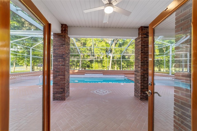 view of swimming pool with glass enclosure, ceiling fan, and a patio