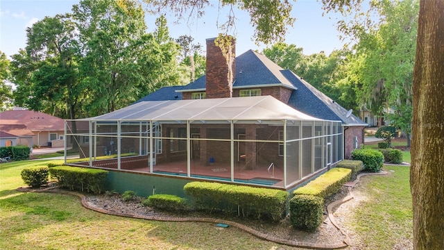 back of property with glass enclosure and a yard