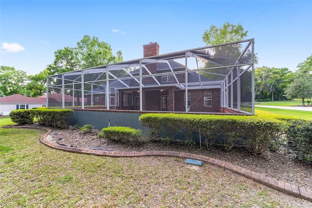 rear view of house with glass enclosure and a yard