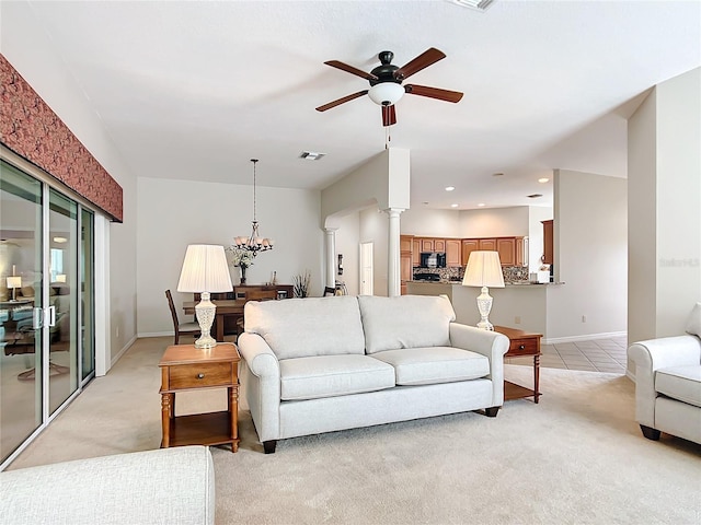 carpeted living room featuring ceiling fan with notable chandelier and ornate columns