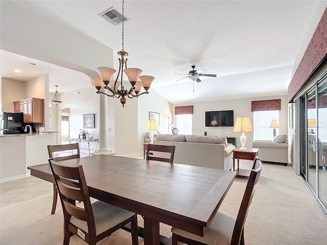 carpeted dining area with ceiling fan with notable chandelier, vaulted ceiling, and ornate columns