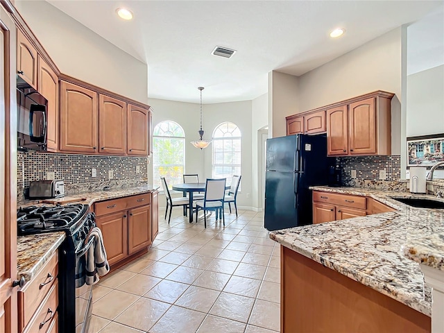 kitchen with black appliances, light stone counters, light tile patterned floors, and sink