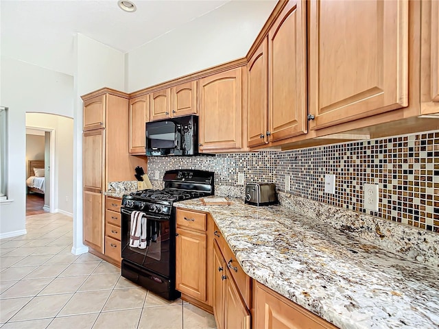 kitchen with black appliances, decorative backsplash, light stone counters, and light tile patterned floors