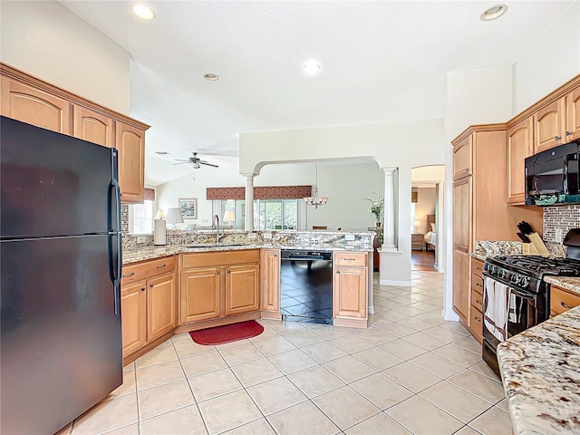 kitchen with light stone counters, vaulted ceiling, ceiling fan, sink, and black appliances