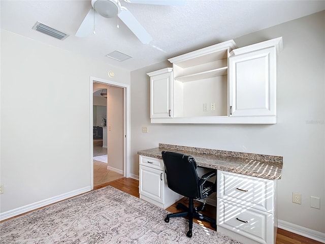 home office featuring ceiling fan, built in desk, and light wood-type flooring