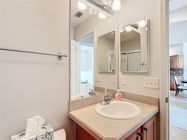 bathroom with tile patterned floors, tasteful backsplash, vanity, and a shower with shower door