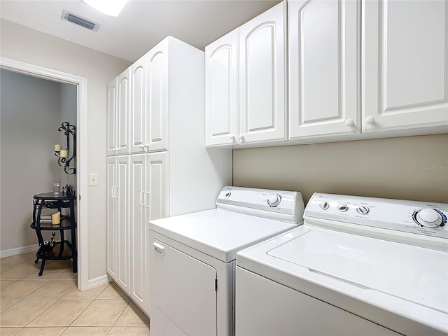 clothes washing area featuring separate washer and dryer, light tile patterned flooring, and cabinets