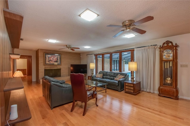 living room featuring a textured ceiling, ceiling fan, and light hardwood / wood-style flooring