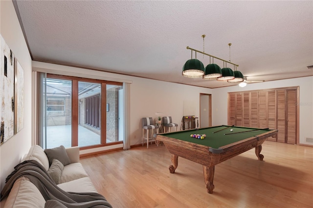 recreation room featuring billiards, a textured ceiling, and light hardwood / wood-style floors