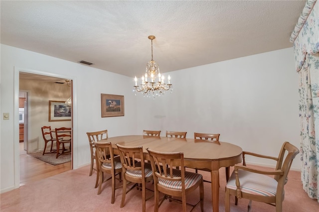 carpeted dining space with a notable chandelier and a textured ceiling