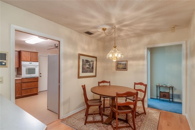 dining space with light hardwood / wood-style floors and a notable chandelier