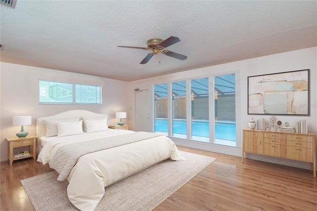 bedroom featuring a textured ceiling, multiple windows, ceiling fan, and light wood-type flooring