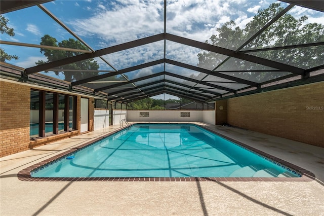 view of pool featuring glass enclosure and a patio area