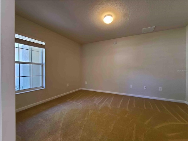 unfurnished room with a textured ceiling and dark carpet