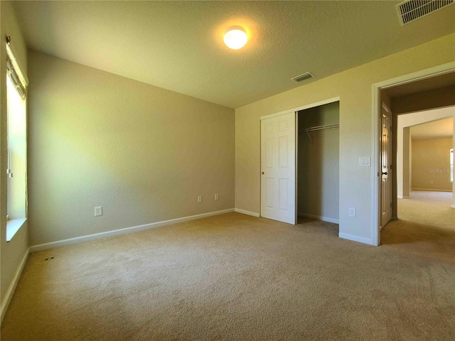 unfurnished bedroom featuring a closet and light carpet