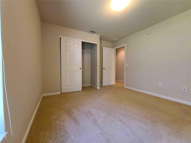 unfurnished bedroom featuring a closet and light colored carpet