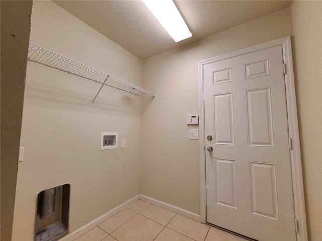 clothes washing area with washer hookup, a textured ceiling, and light tile floors