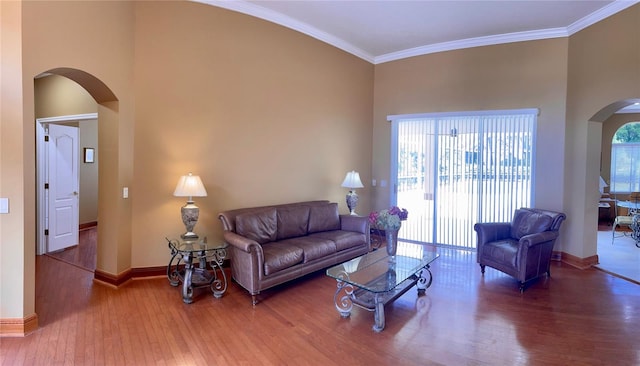 living room featuring crown molding, dark hardwood / wood-style flooring, a wealth of natural light, and a towering ceiling