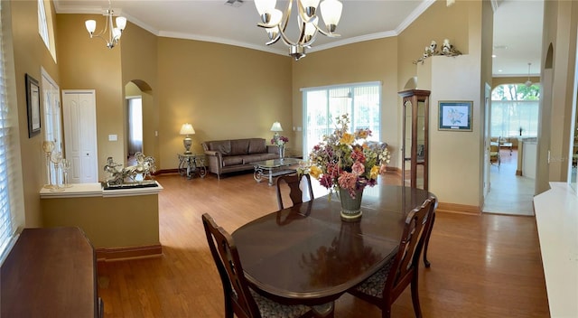 dining space with crown molding, wood-type flooring, and a chandelier