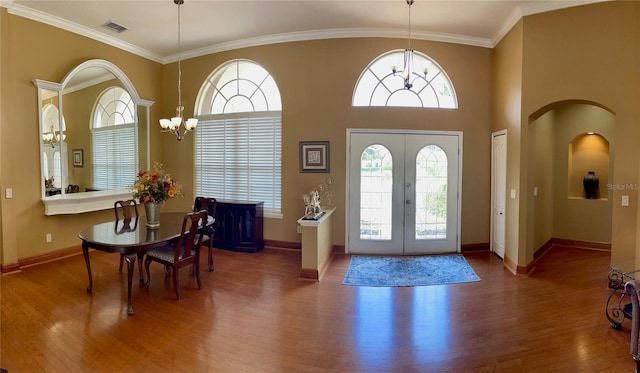 foyer with ornamental molding, dark wood-type flooring, a chandelier, and french doors