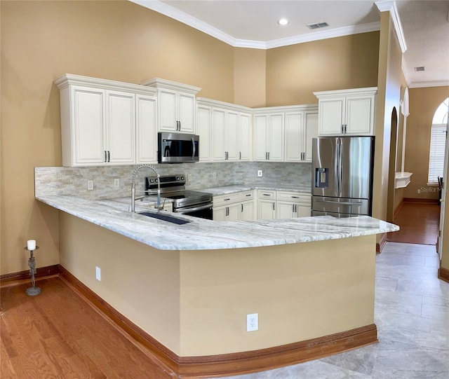 kitchen with appliances with stainless steel finishes, crown molding, kitchen peninsula, and white cabinets