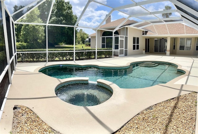 view of pool with glass enclosure, a patio area, and an in ground hot tub