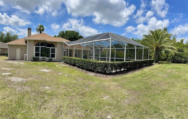 back of property featuring glass enclosure and a yard