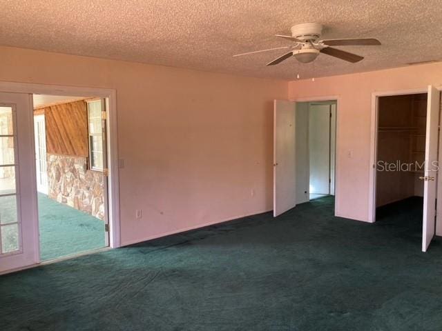 interior space featuring dark colored carpet, ceiling fan, and a textured ceiling