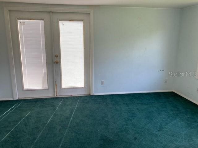 carpeted spare room with plenty of natural light and french doors