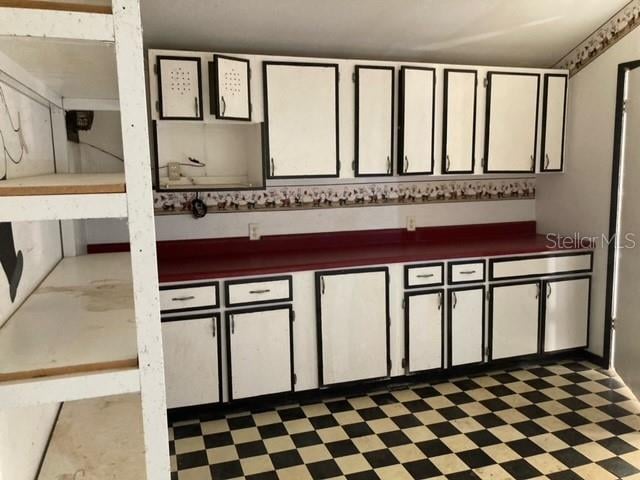 kitchen featuring white cabinets and dark tile floors